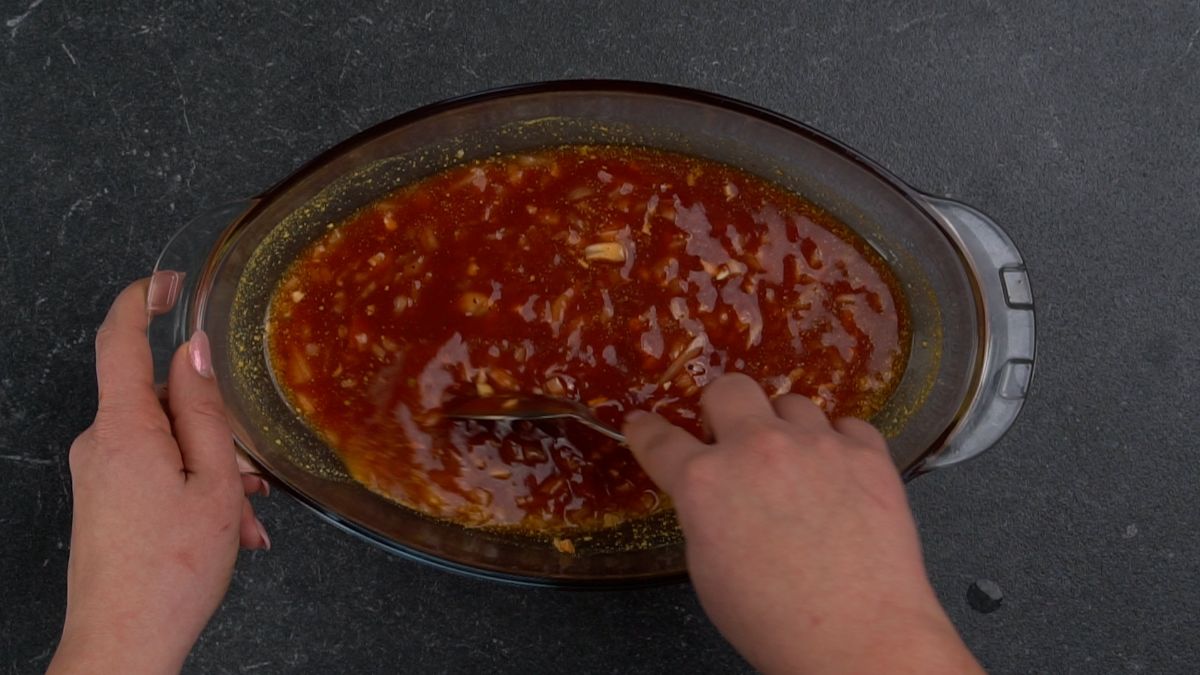 barbecue sauce being mixed in glass baking dish