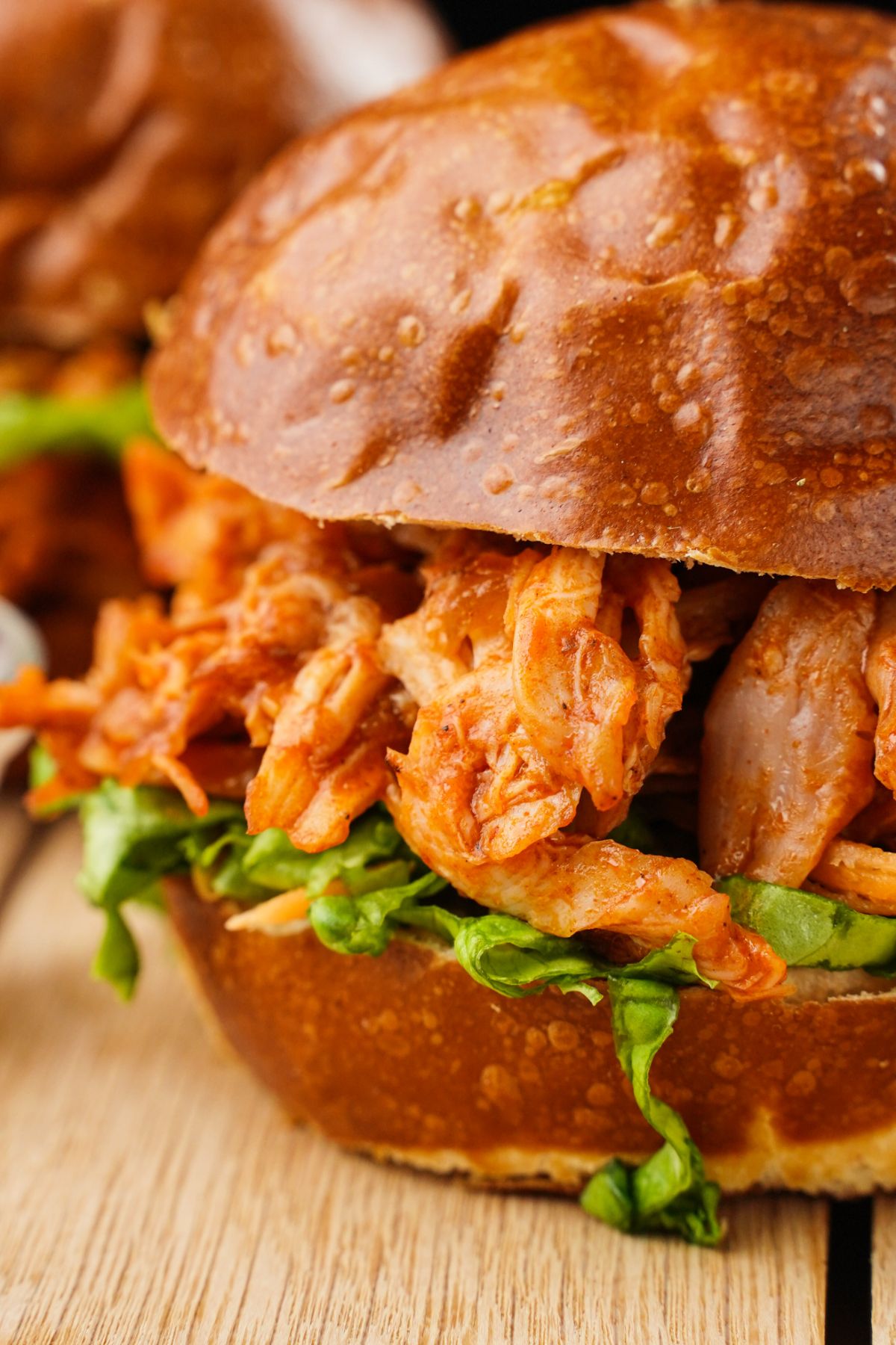 close up of side of pulled chicken sandwich on wooden table