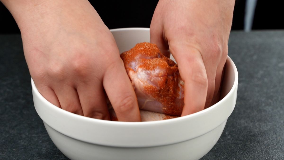 hands rolling chicken legs in spices
