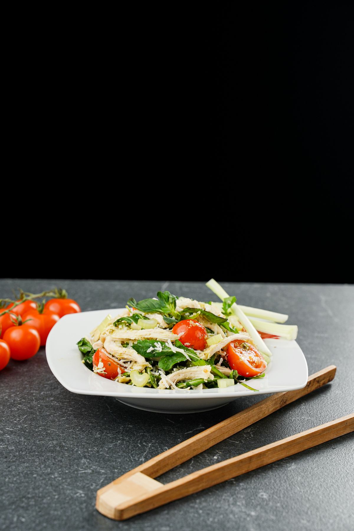 white plate of salad on gray table with black background