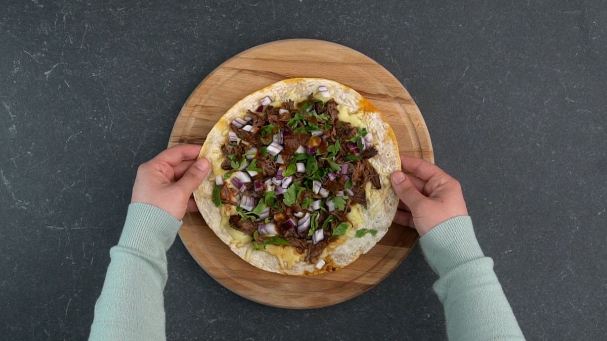 hands holding second birria tortilla on top of first