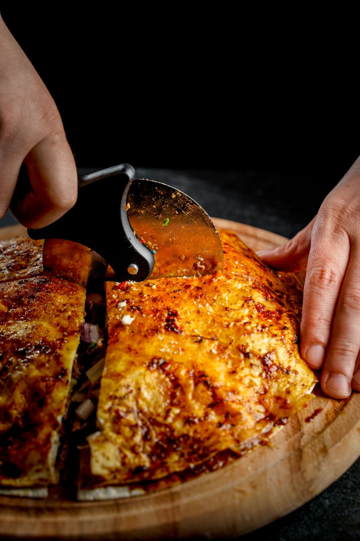 hand cutting pizza on cutting board
