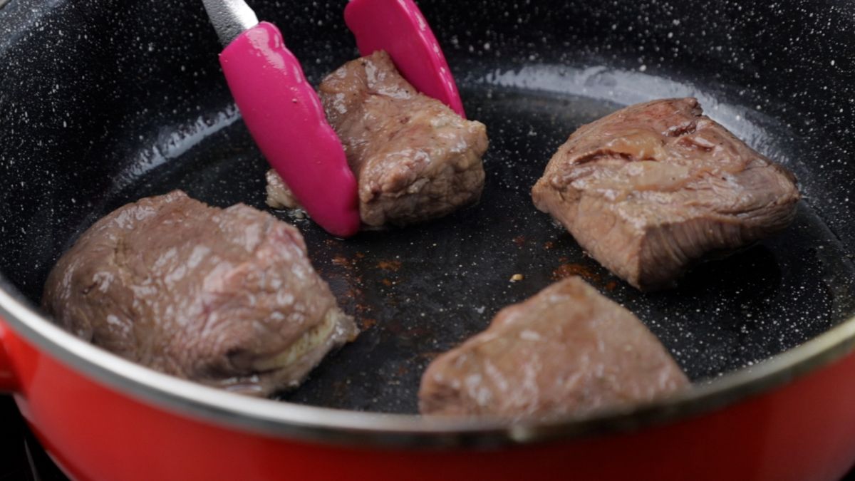 beef chunks being seared in skillet