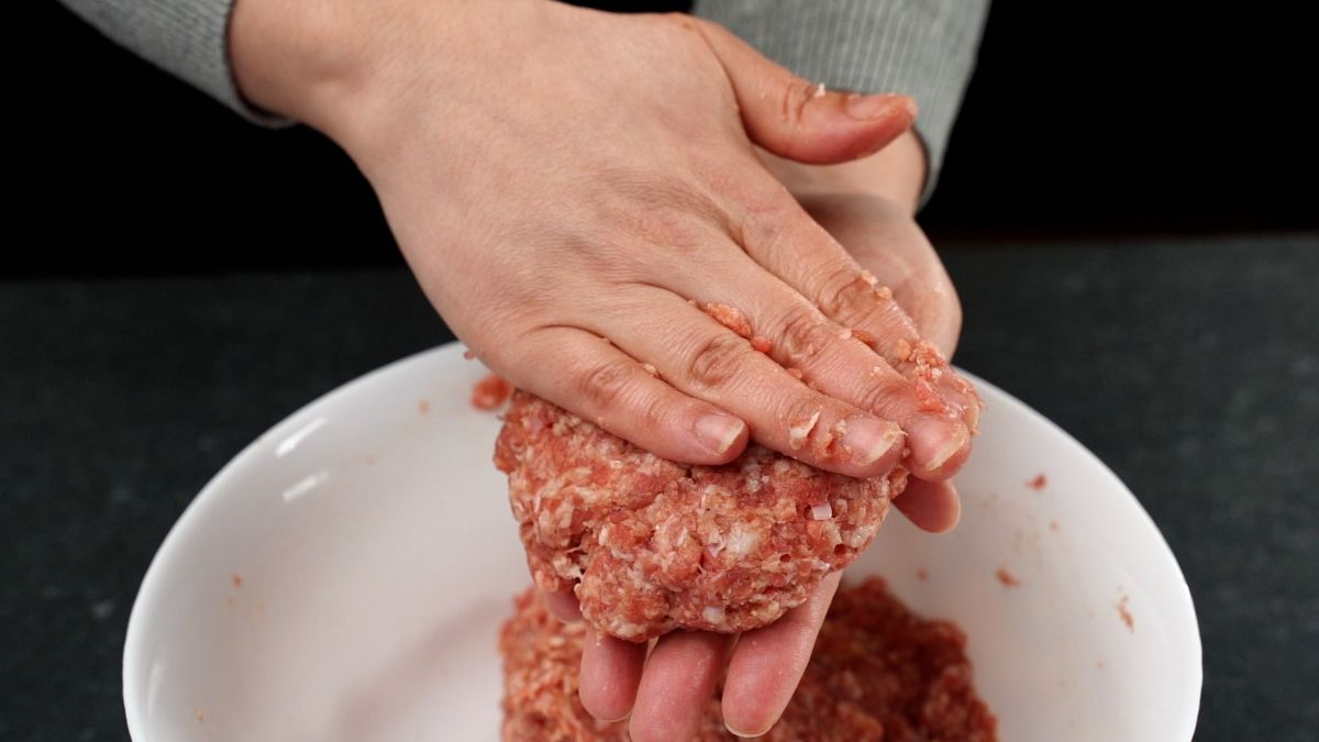 hands forming burger patty above white bowl