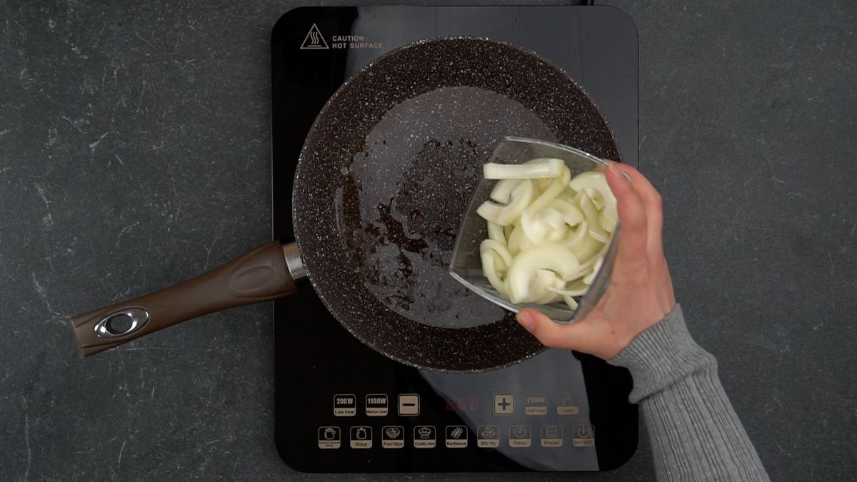 hand adding onions to skillet
