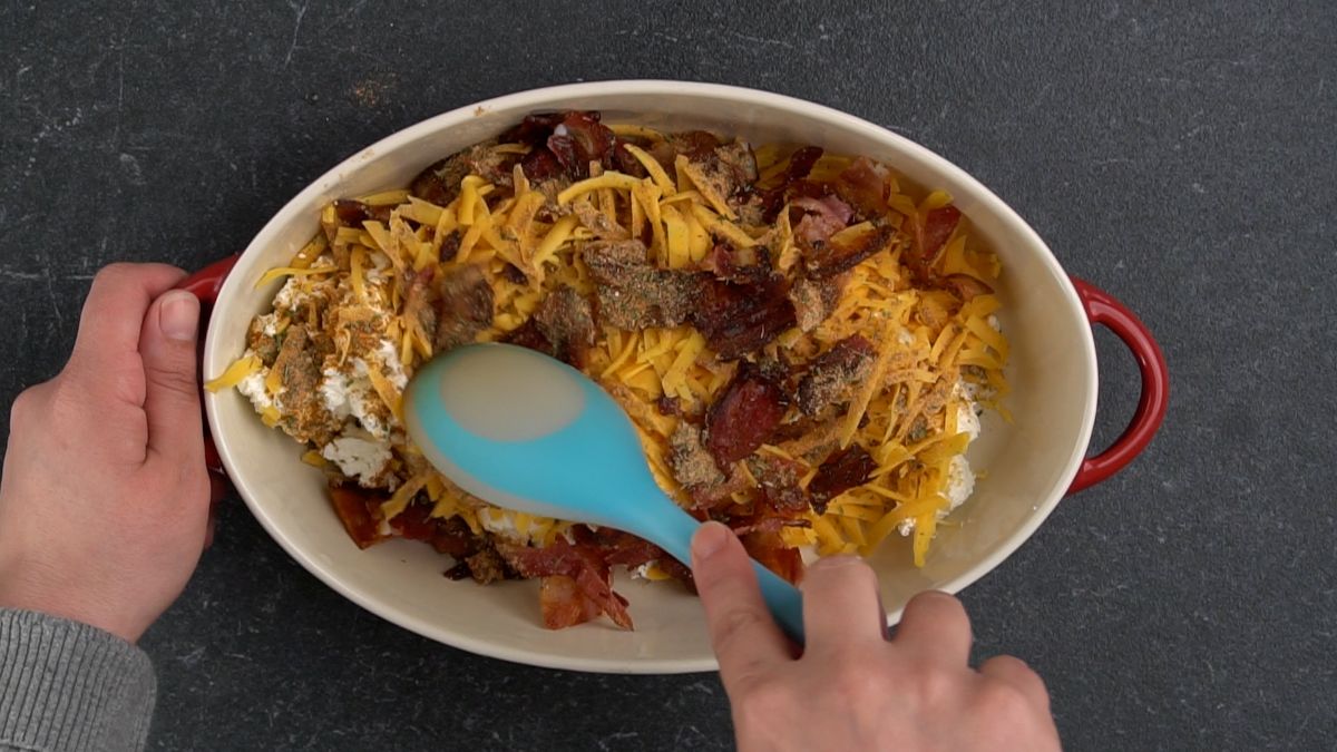 blue spoon in baking dish with bacon and cheese