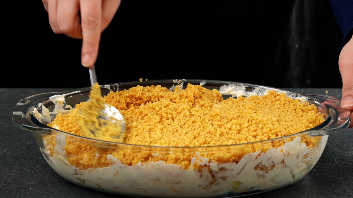spoon spreading cornflakes on top of potatoes