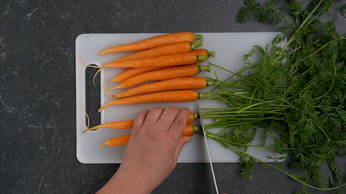 hand trimming greens off end of carrots
