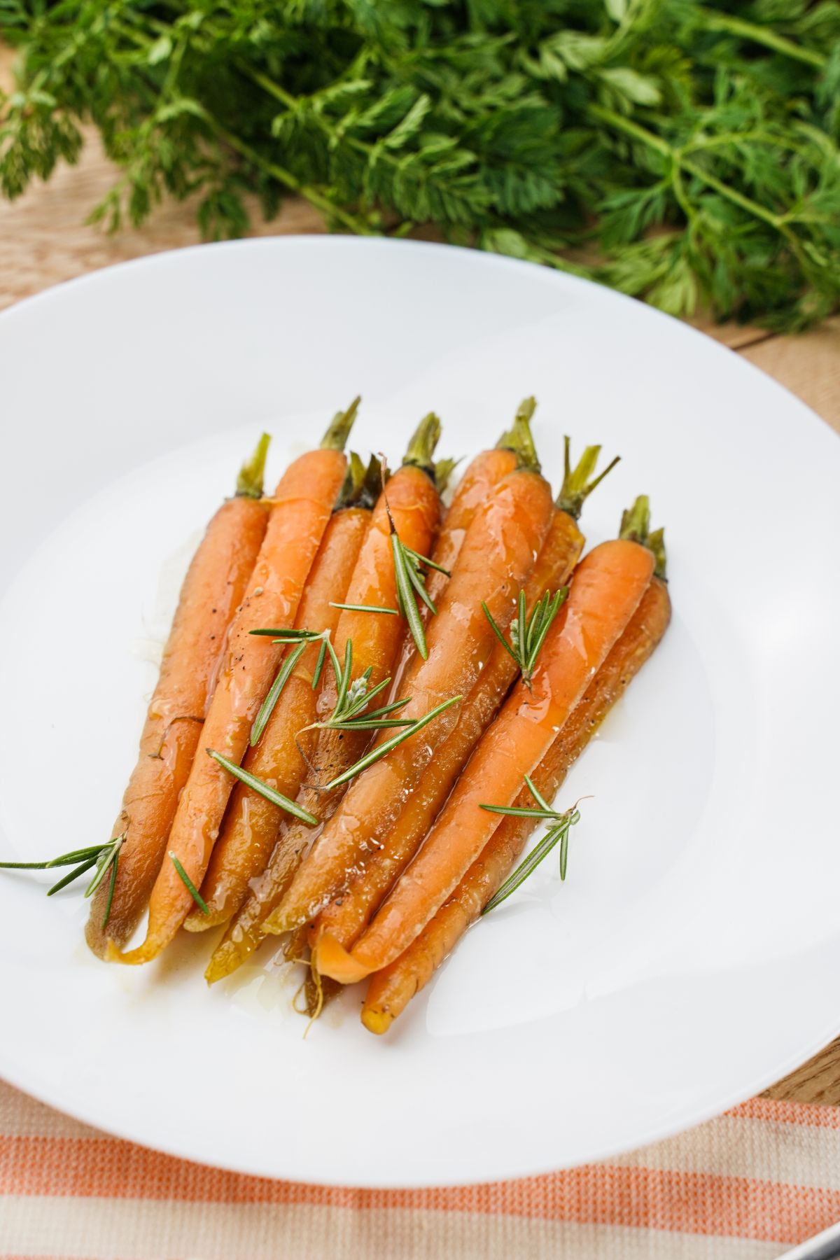 round white plate on table topped with cooked carrots and herbs