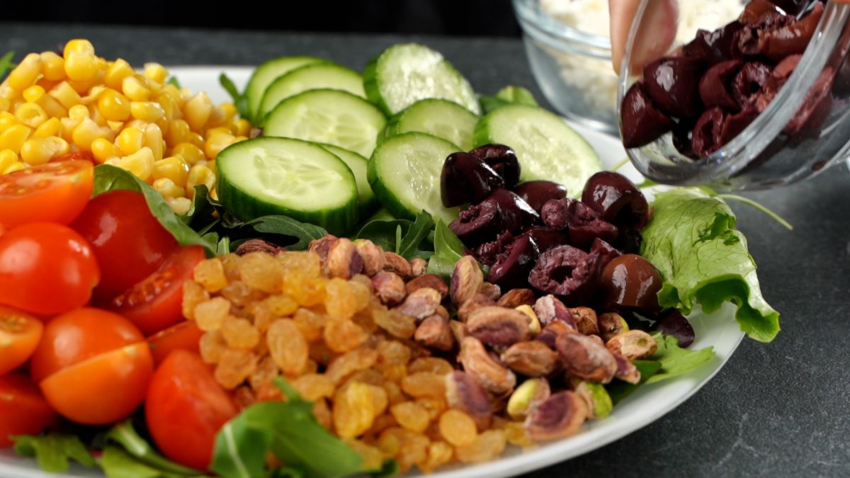plate of salad toppings with olives on side