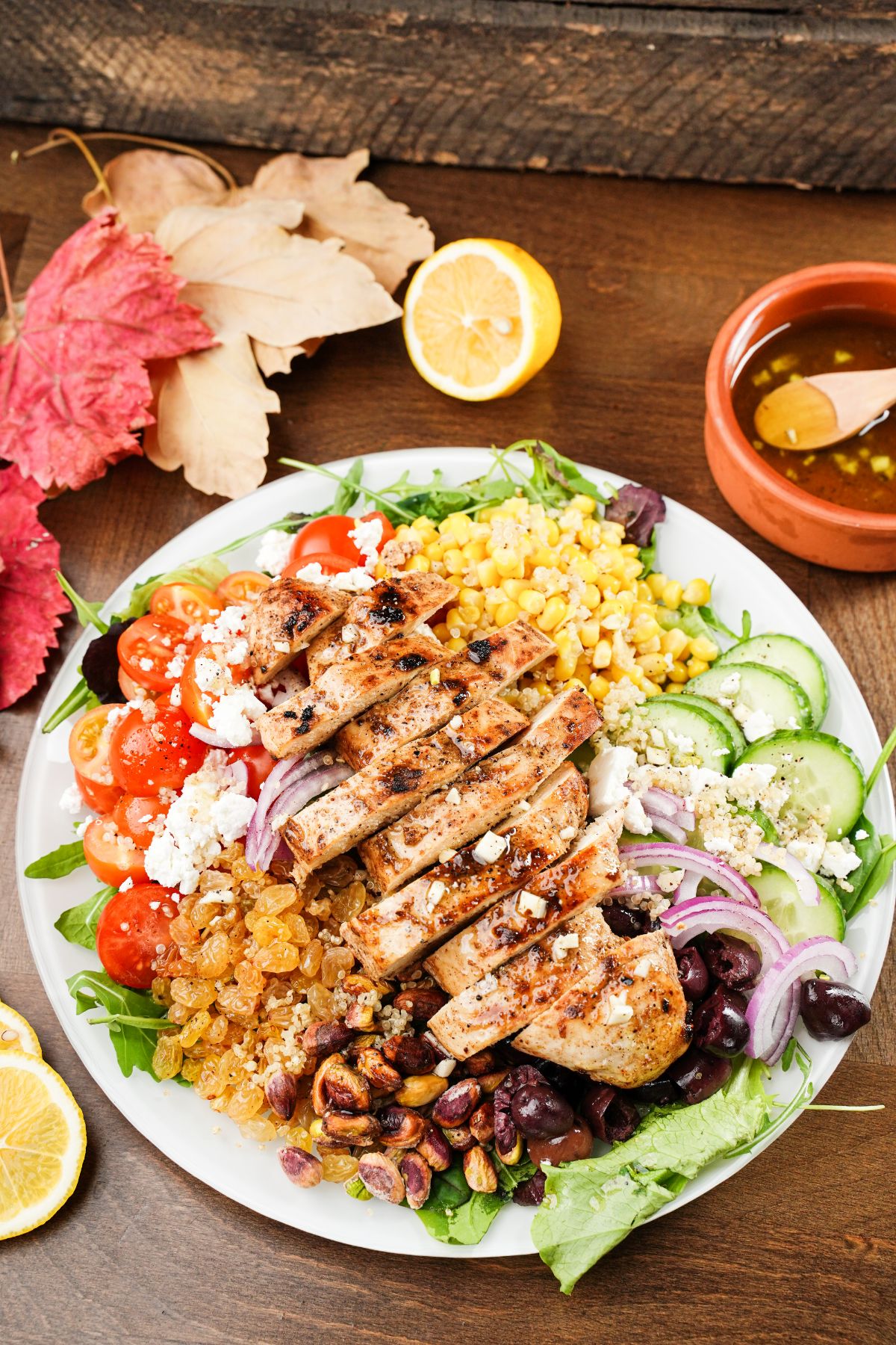 white plate of Greek grilled chicken salad on wood table
