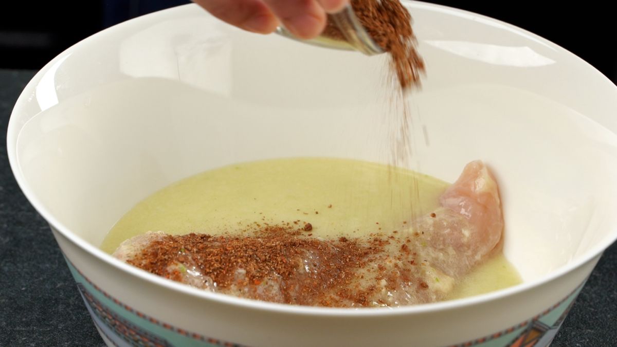 adding chicken and shawarma spice in bowl with marinade