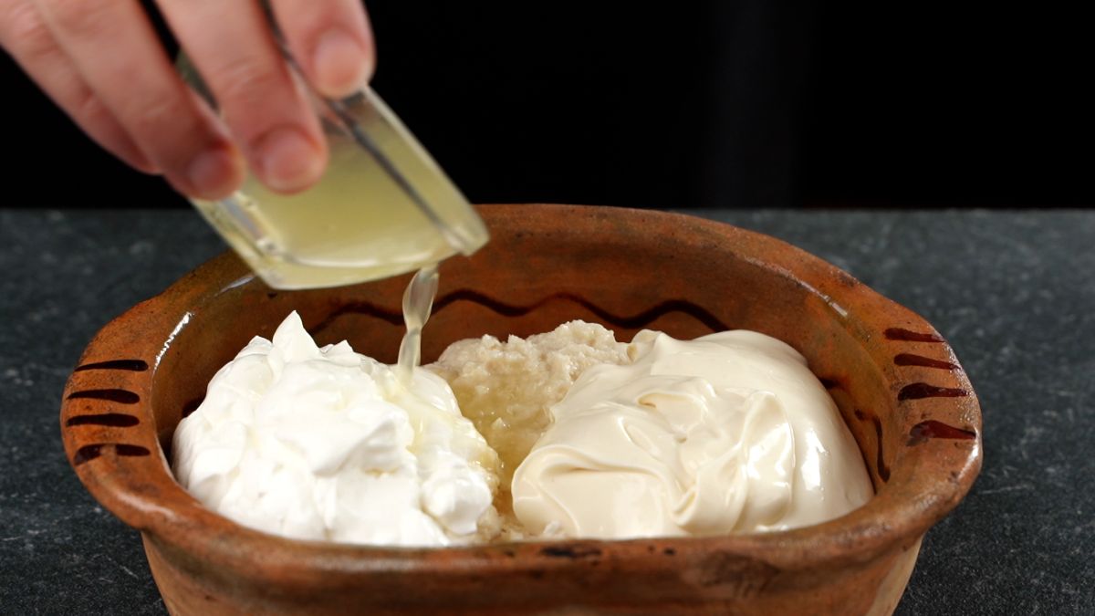 clear bowl of lemon juice being poured into bowl with sour cream
