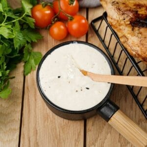 round black bowl of horseradish sauce with wooden spoon next to black wire basket