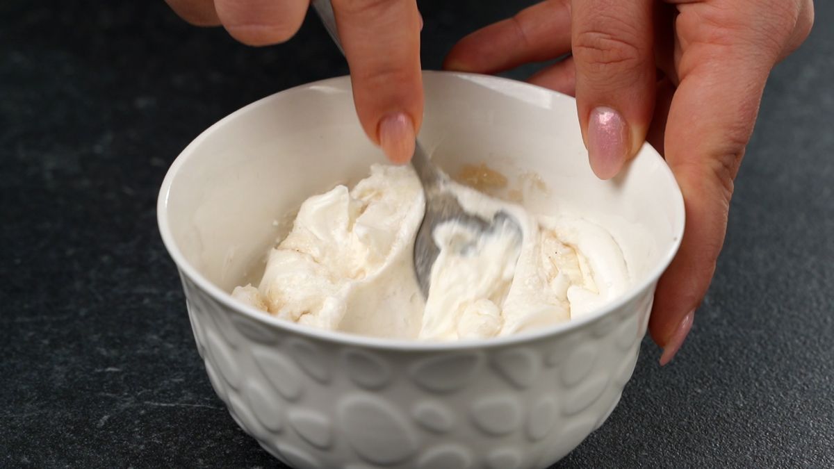 hand stirring crema cheese in white bowl