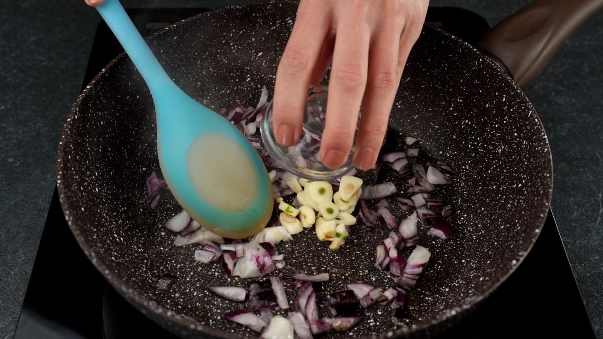 onion and garlic being poured into skillet