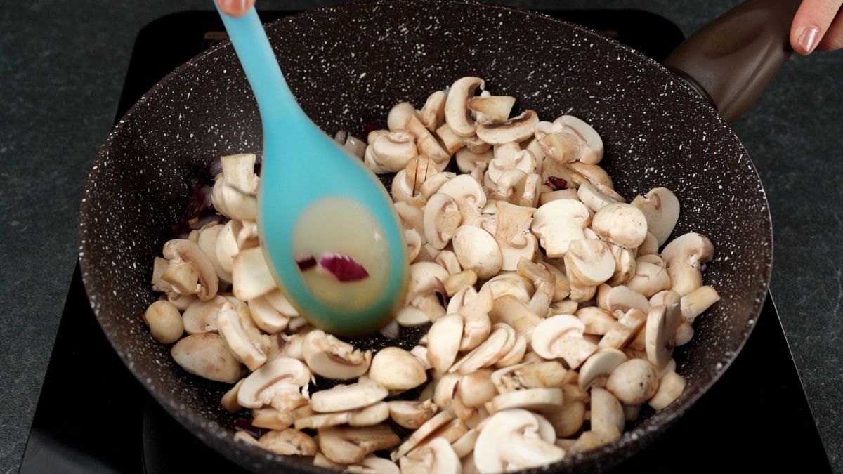 raw mushrooms and blue spoon in skillet