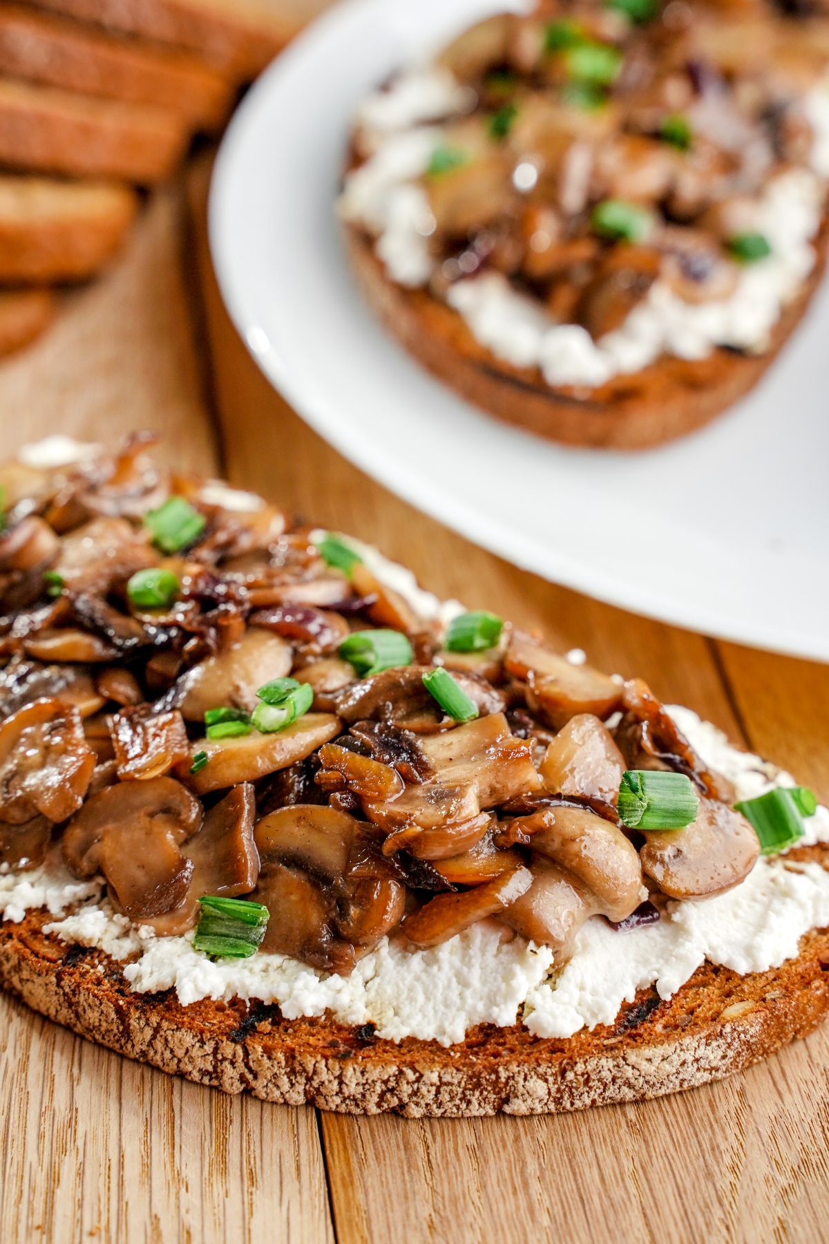 mushroom ricotta toast by white plate of toast