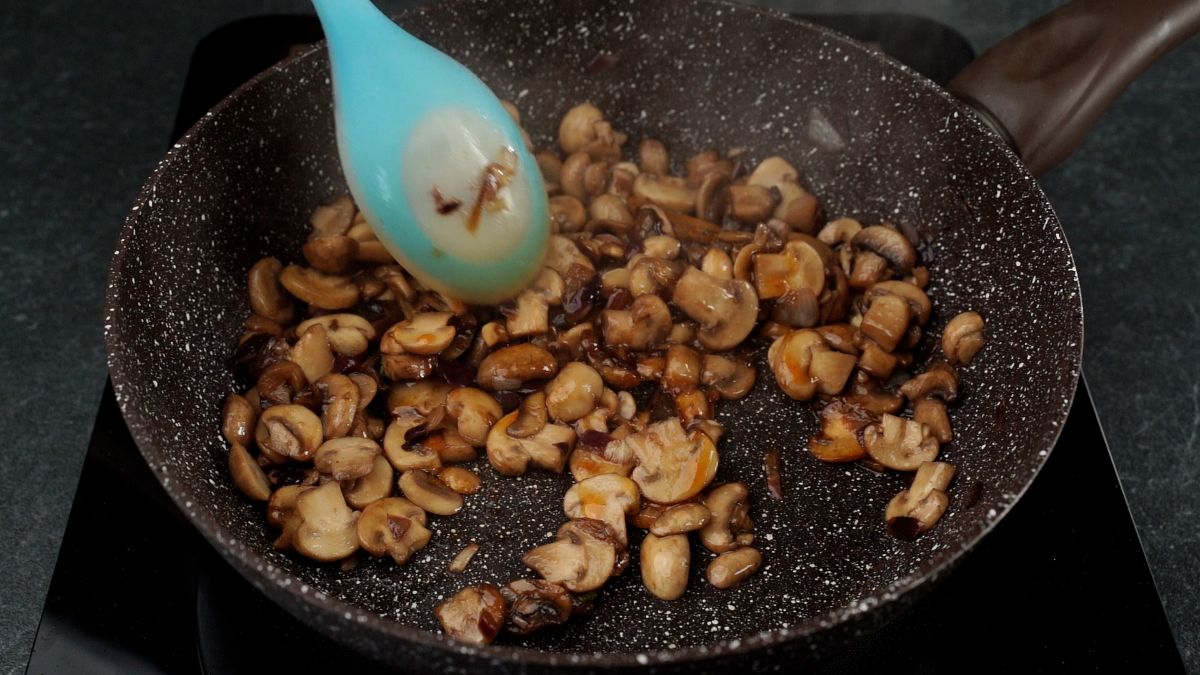 skillet of mushrooms with blue spoon