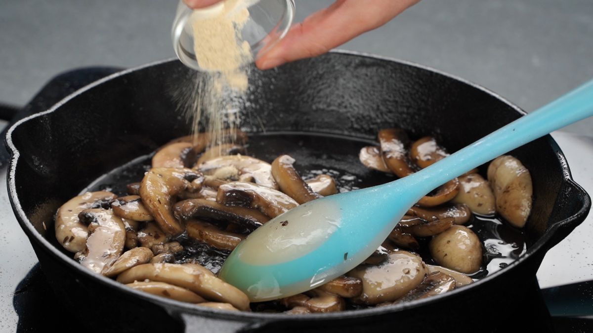 seasoning being poured into skillet with mushrooms