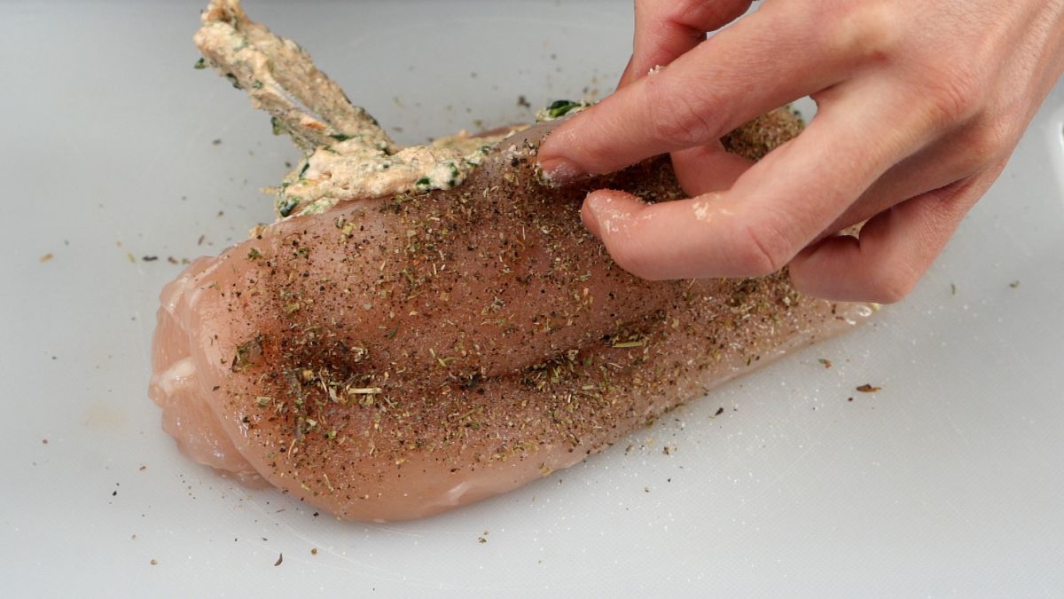 hand stuffing raw chicken breasts