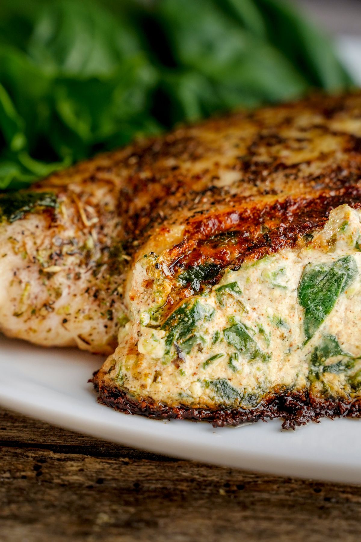 two chicken breasts with cheese and spinach on white marble plate