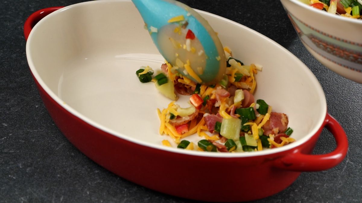 blue spoon putting vegetables into casserole dish