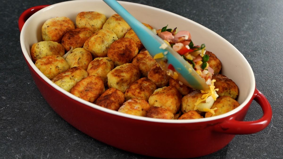 vegetables being added to casserole on top of tater tots
