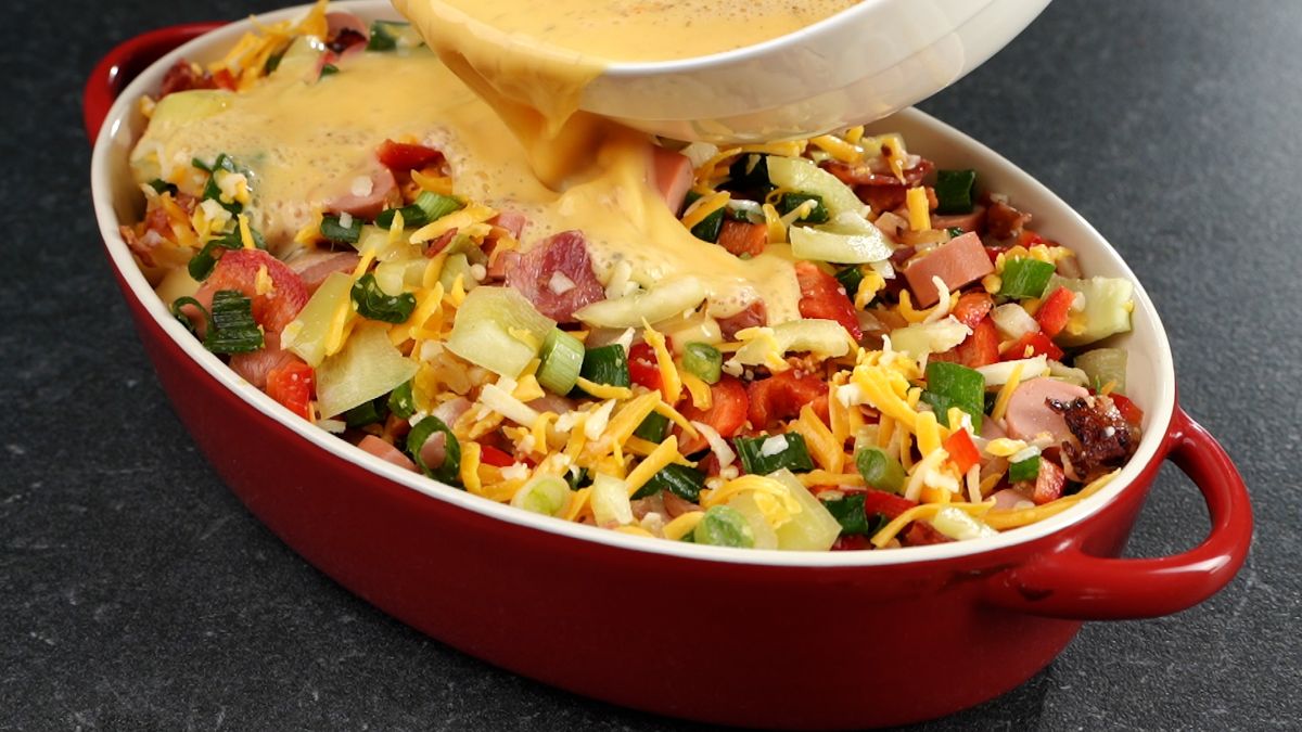 eggs being poured over vegetables in casserole dish