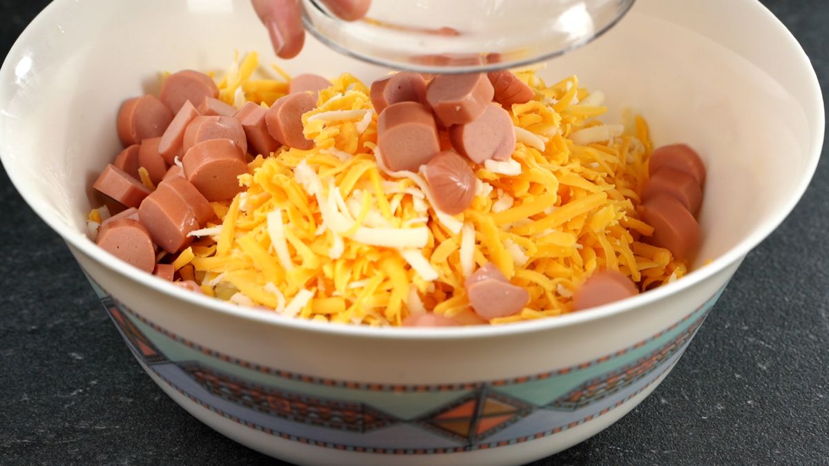 adding sausage to cheese in white bowl