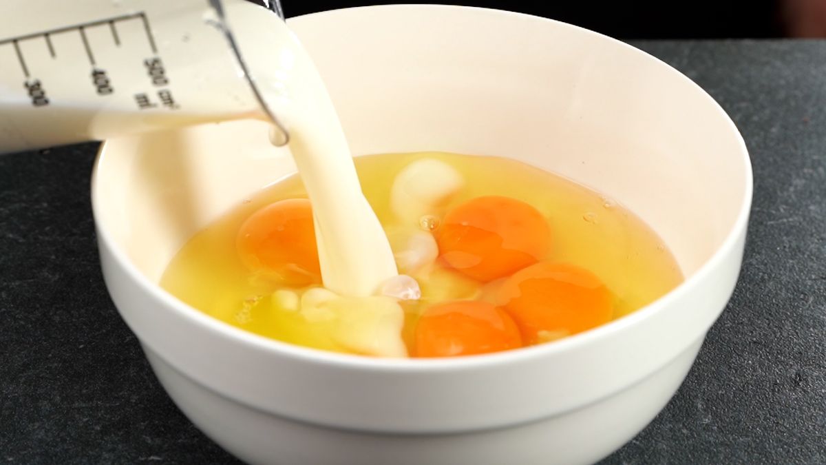 cream being poured into white bowl of cracked eggs