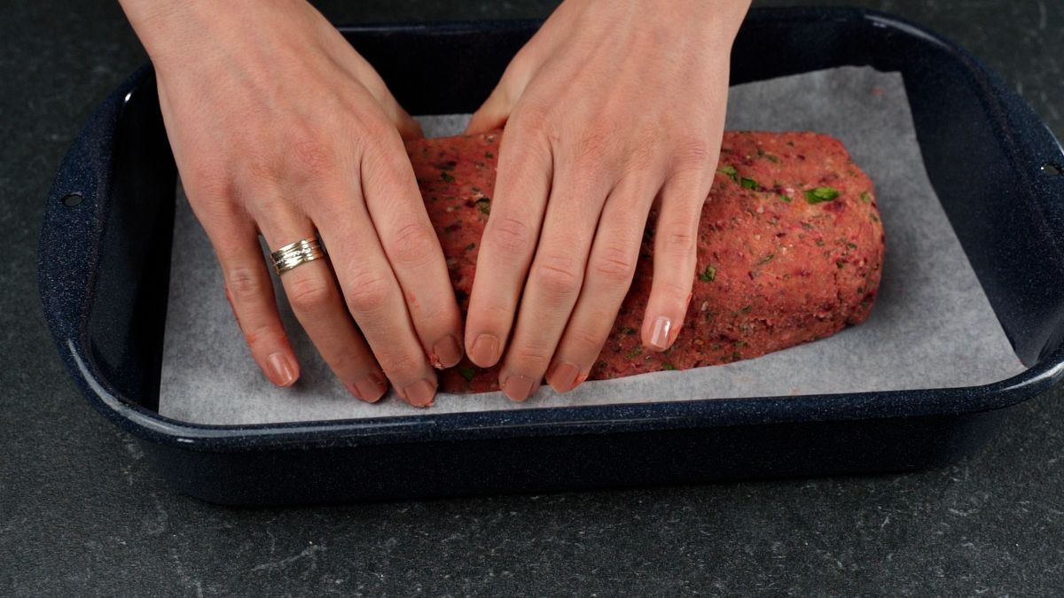 hand forming meatloaf on parchment paper lined baking sheet