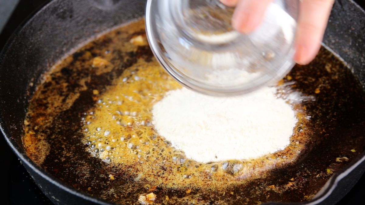 flour being poured into butter in skillet