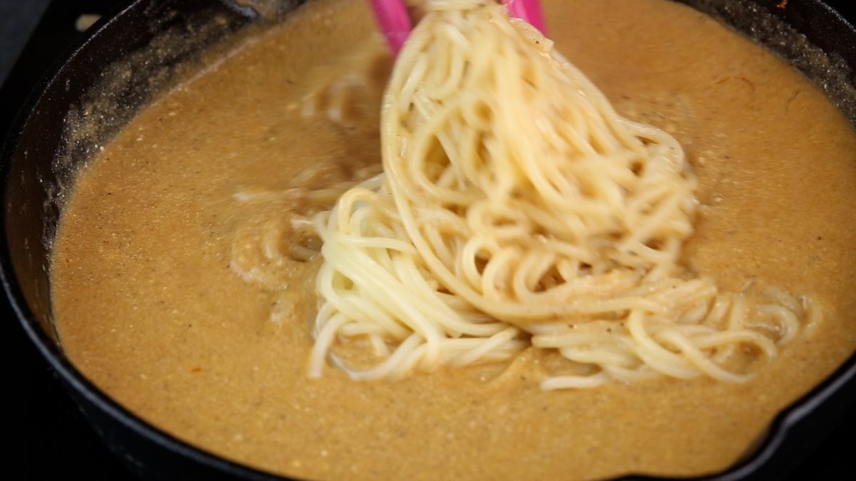 pasta being added to sauce in skillet