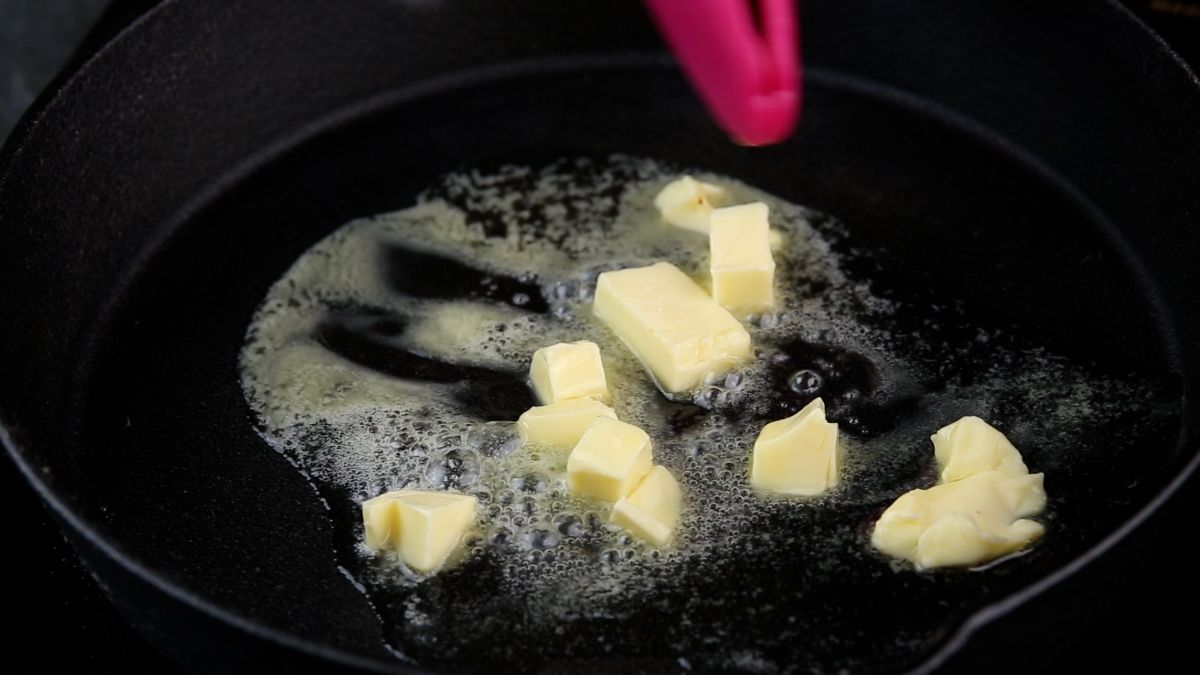 butter in skillet with pink tongs