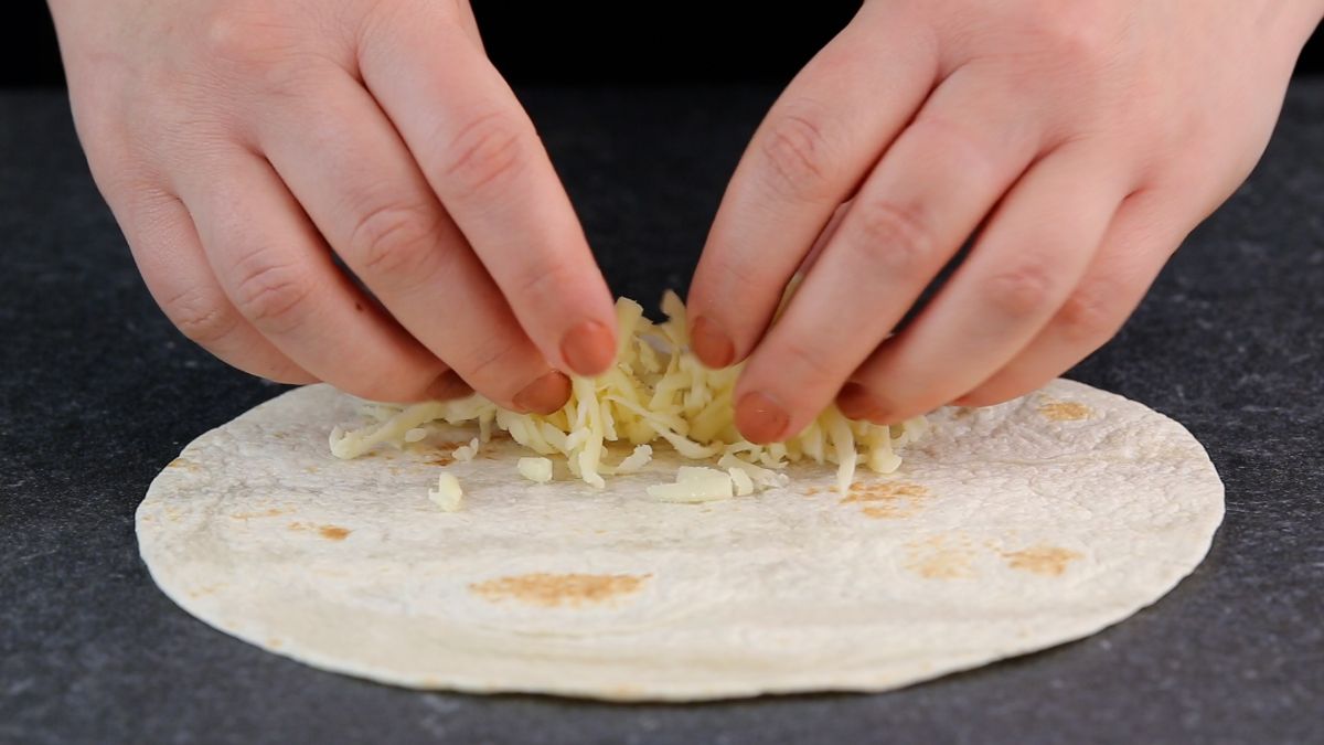cheese being added to middle of tortilla