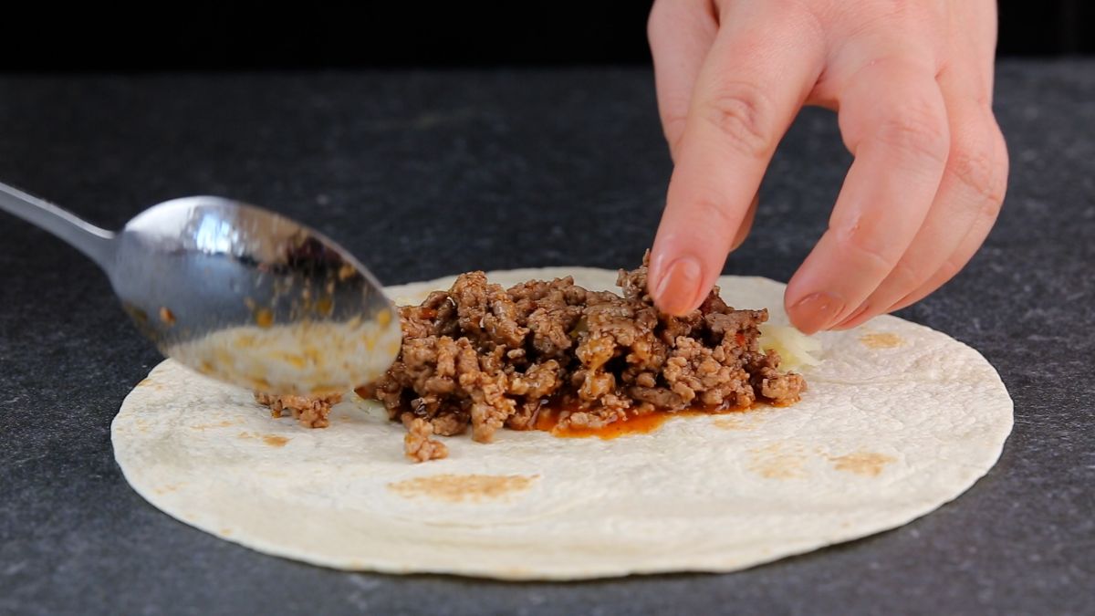 meat being placed on middle of tortilla
