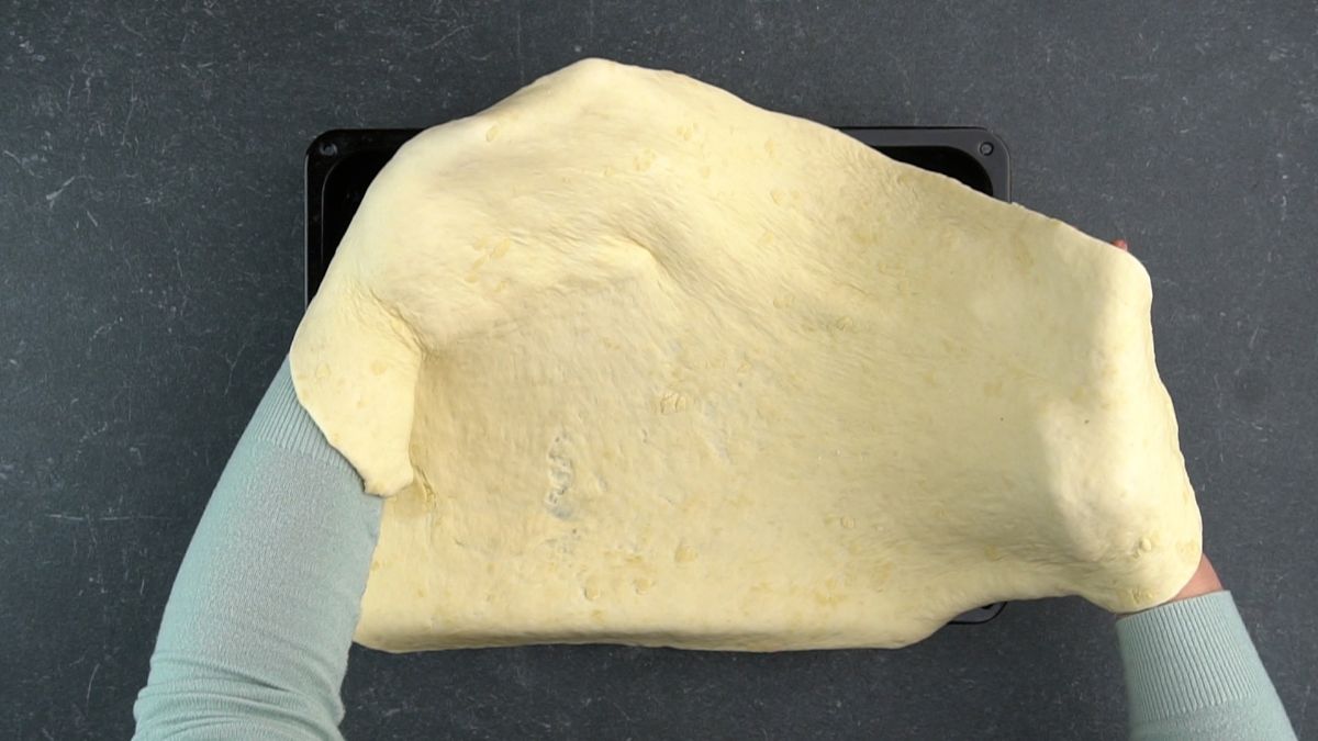 dough being spread over baking sheet