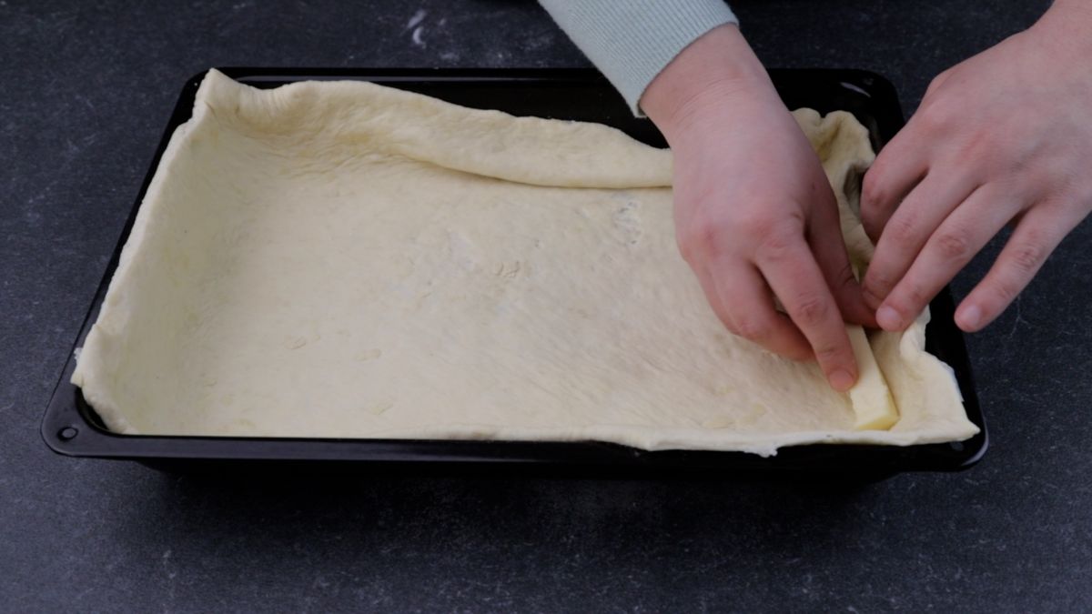cheese being added around crust for pizza