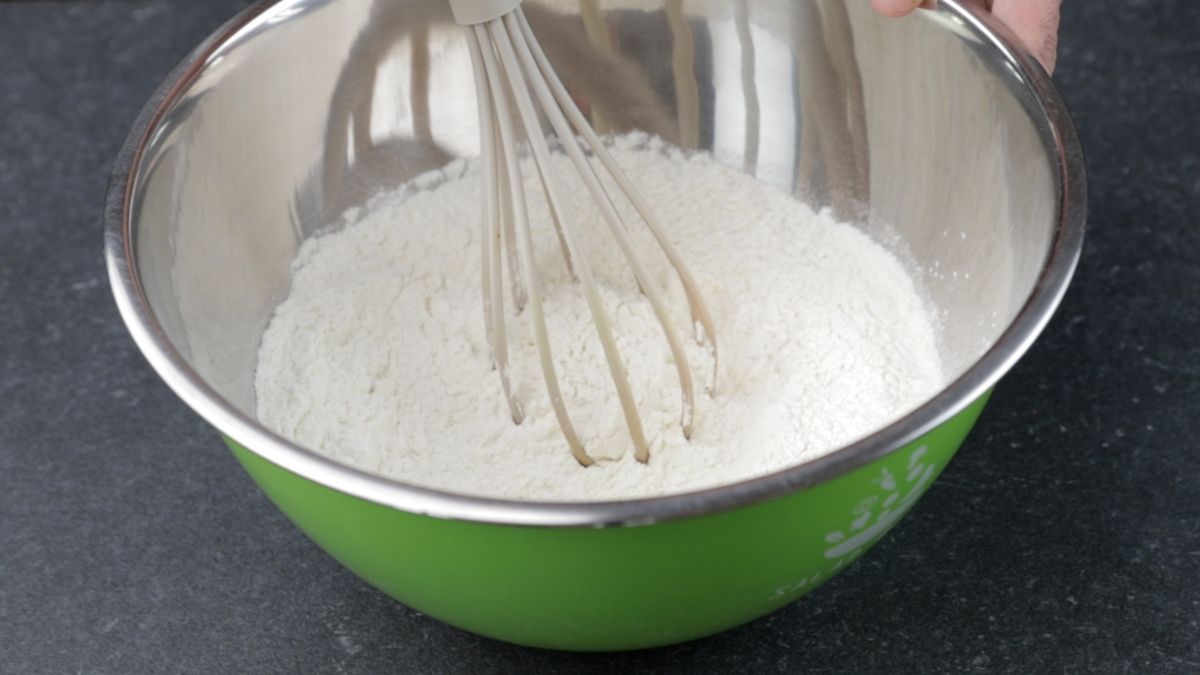 stainless steel bowl of flour and whisk