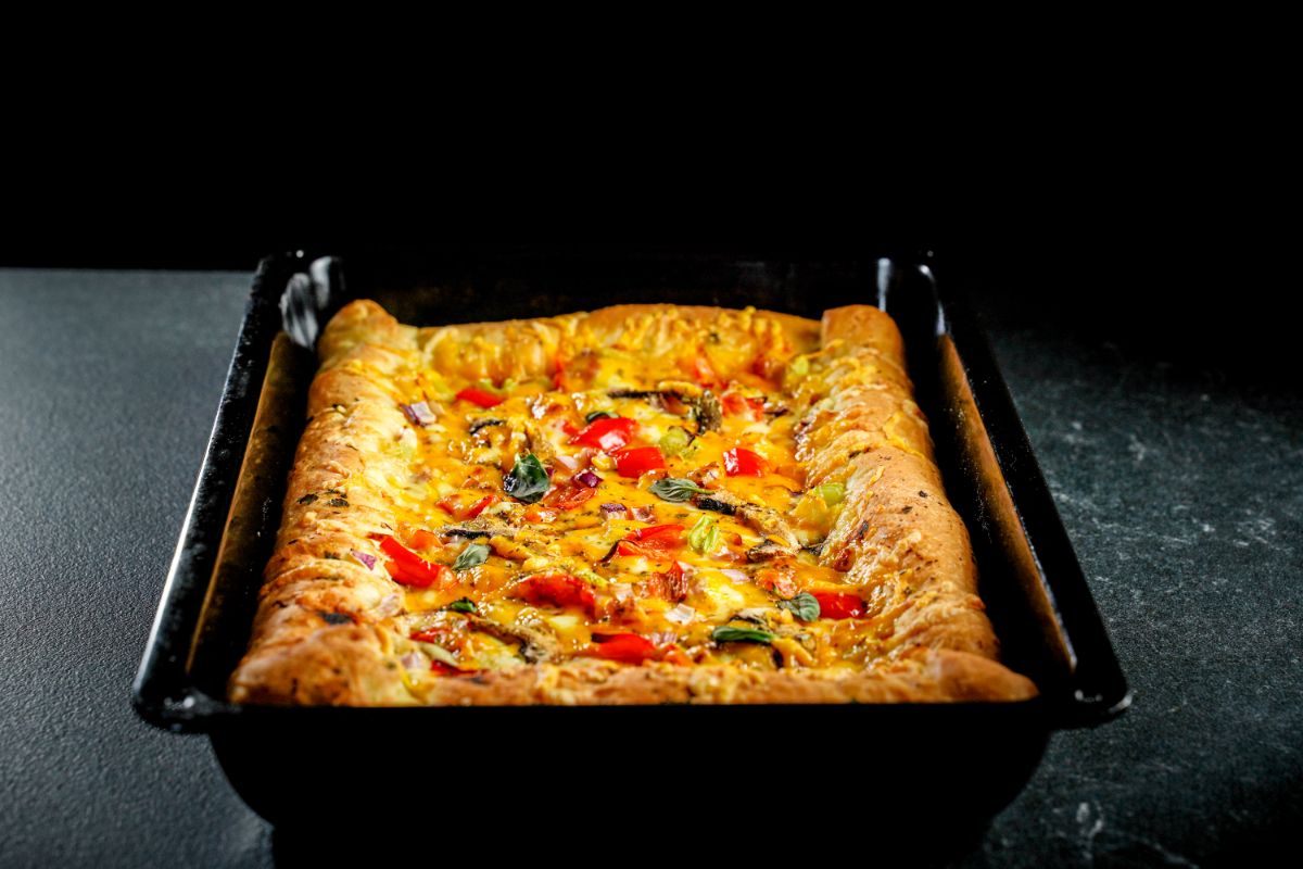 rectangle black pan filled with vegetable pizza