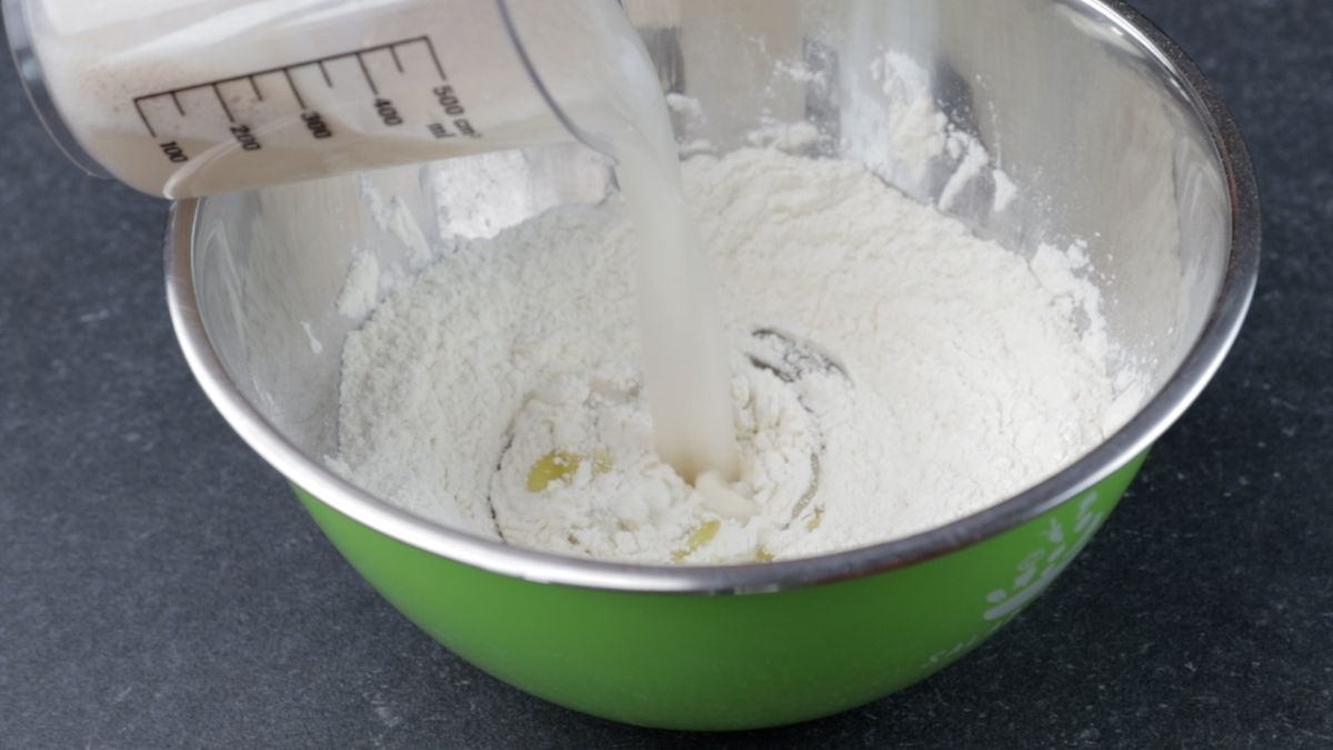 yeast being poured into bowl of flour