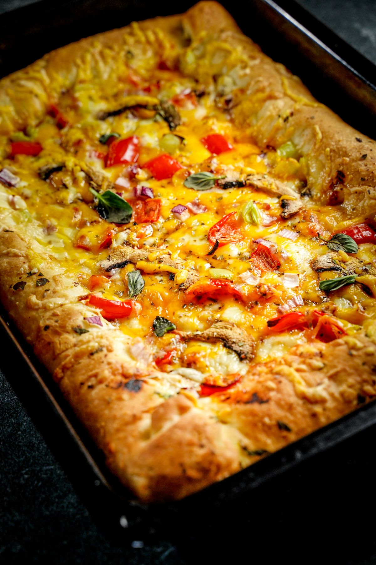 stuffed crust pizza with vegetables in black pizza pan