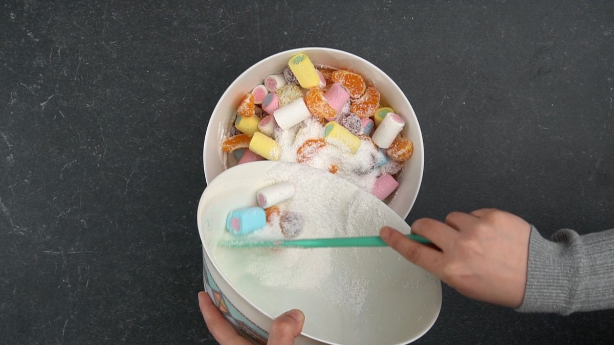hand spooning whipped cream into bowl with fruit