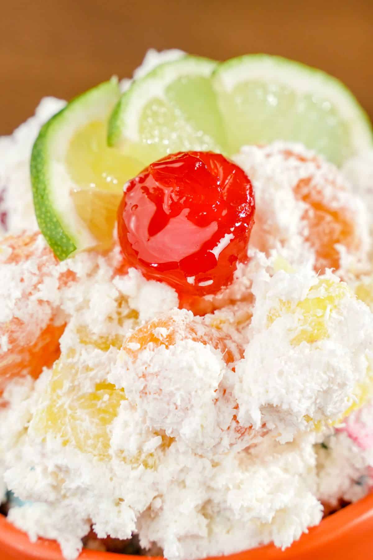close image of ambrosia salad topped with cherries and lime slices