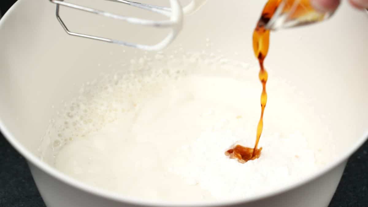 heavy cream in bowl with vanilla being poured over the top