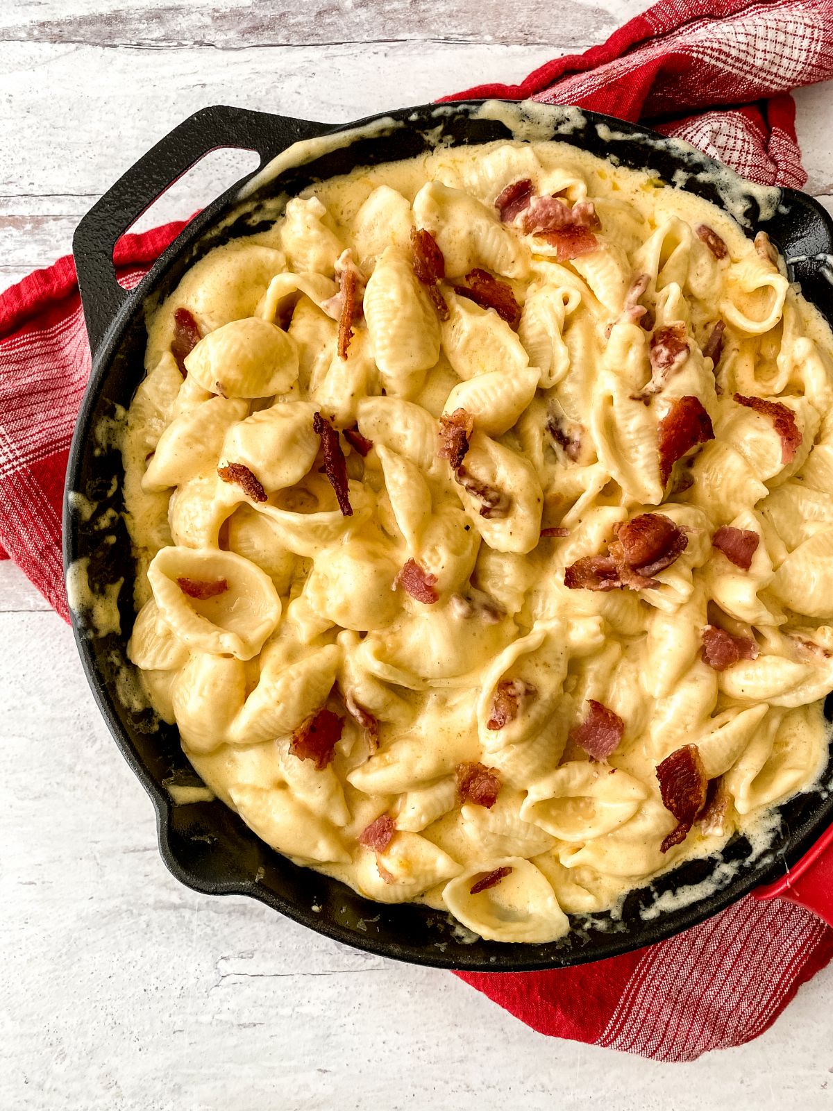 cast iron skillet on red napkin filled with bacon shells and cheese