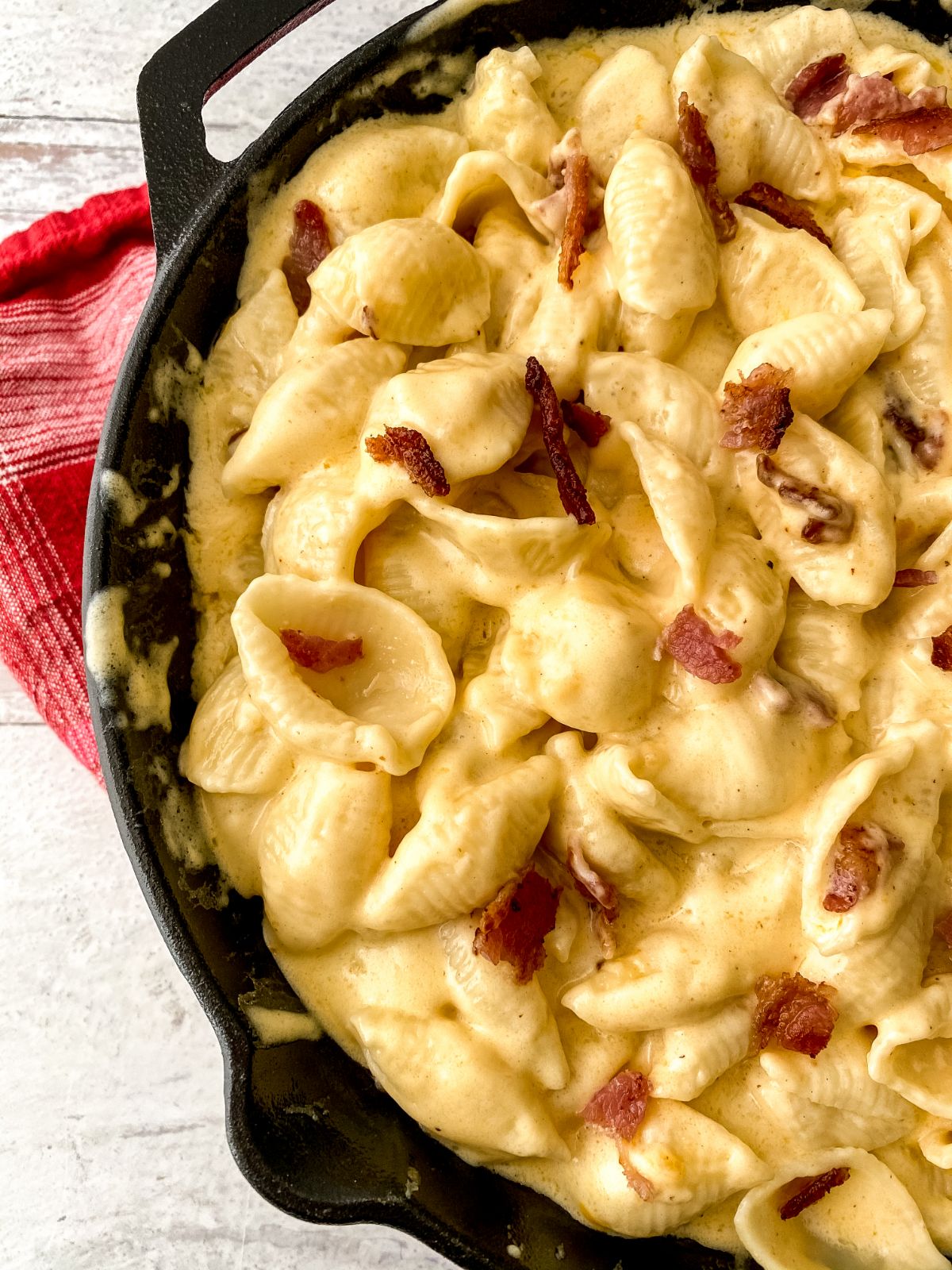 cast iron skillet filled with macaroni and cheese on table with red napkin