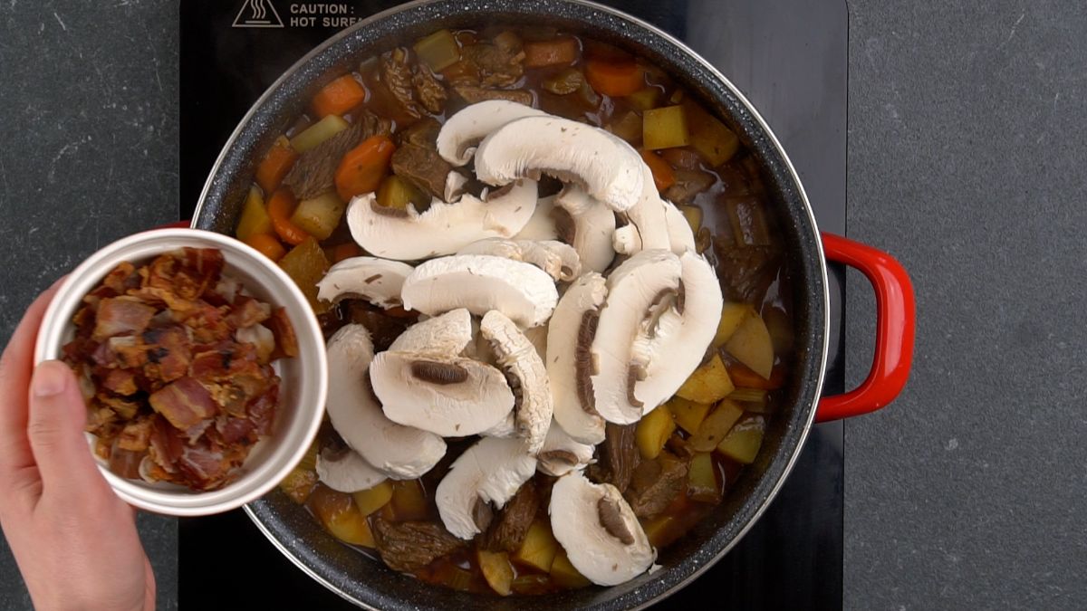 mushrooms and bacon being added to stew