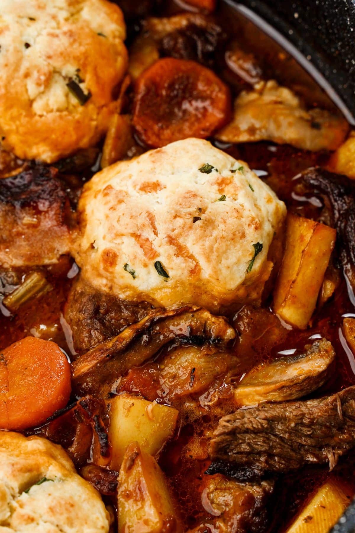close up of beef stew with cheddar biscuit on top